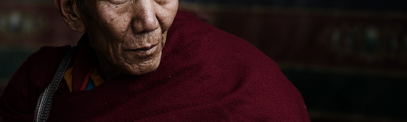 Old Tibetan monk, serene out look. Suffering is attachment.