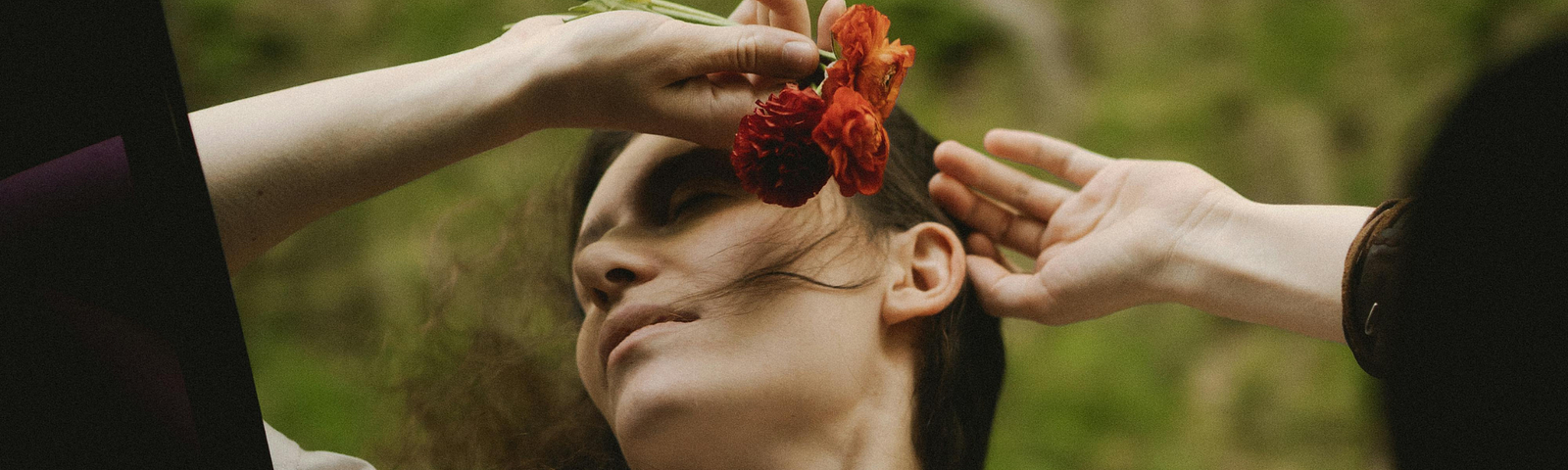 An image of a woman holding a flower, her hair flowing in the breeze, embodying well-being and liberation in the present moment.