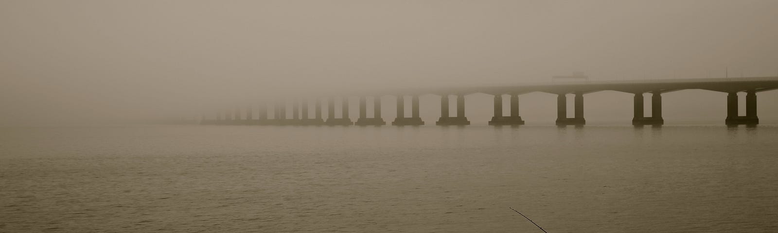 A sepia image of a long bridge over the Severn Estuary. The bridge disappears into fog. In the foreground is a fisherman. The picture represents the unknowable future of mankind and the Earth.
