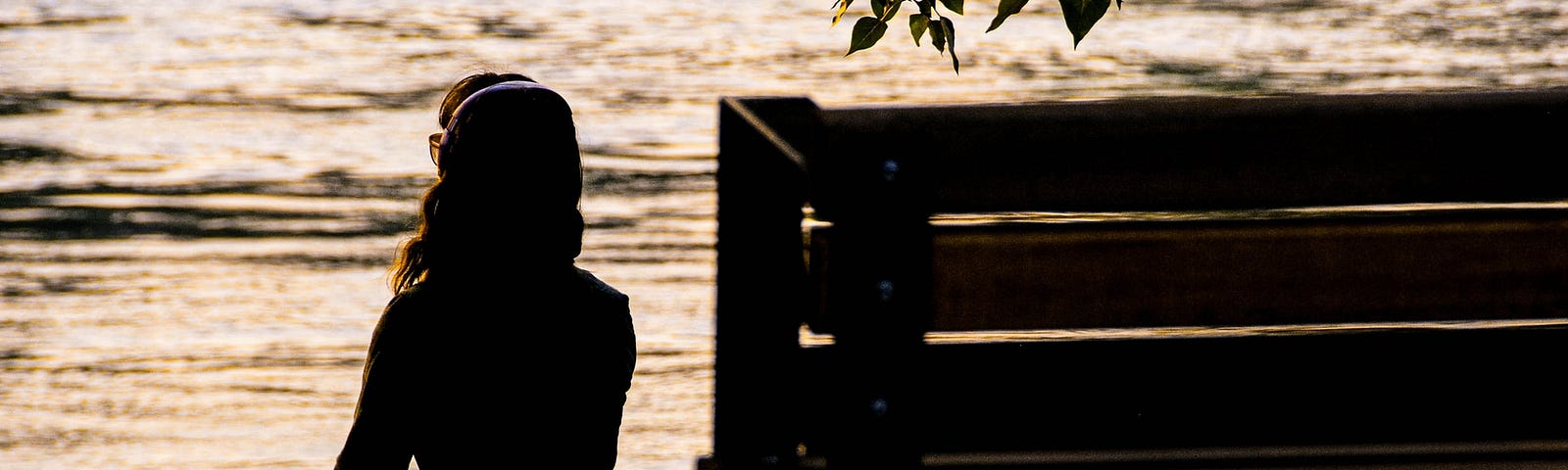 woman sitting next to a bench in front of a lake at dusk