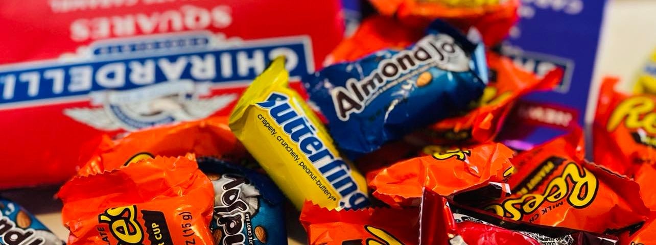 A messy pile of American candy bars including Reese’s, Butterfinger, Mounds, Heath, and Almond Joy.