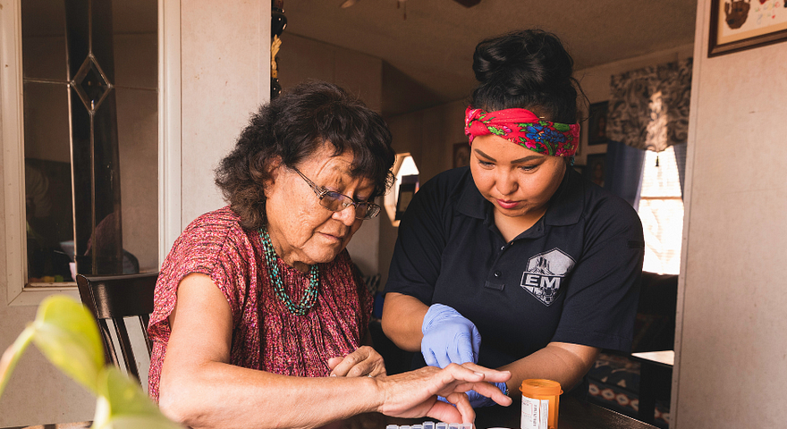 Mujer tribal nativoamericana con una persona joven trabajando en seleccionar medicamentos en una mesa.