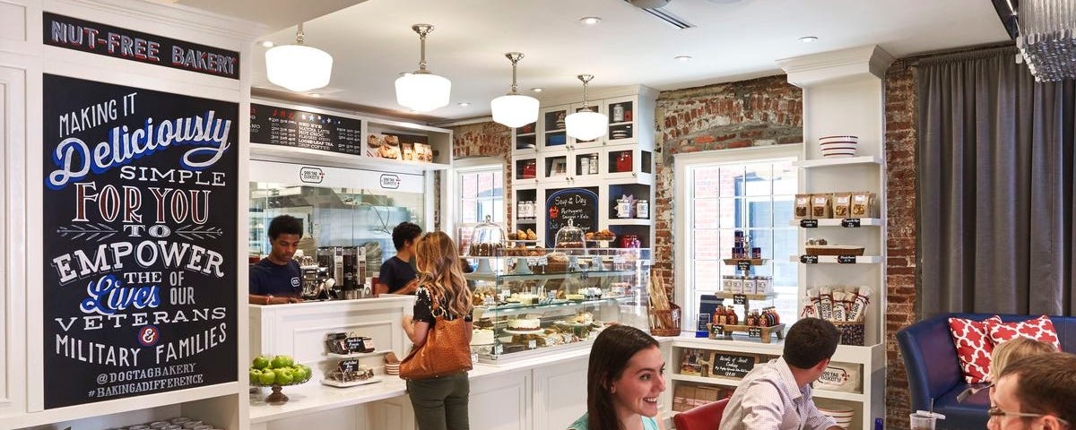 Interior of a bakery with patrons ordering at a counter and sitting at tables eating and drinking. Photo courtesy of Dog Tag Inc.