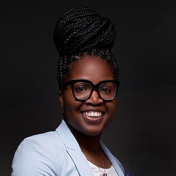 KU student Breanna Bell is pictured in a light blazer against a dark background