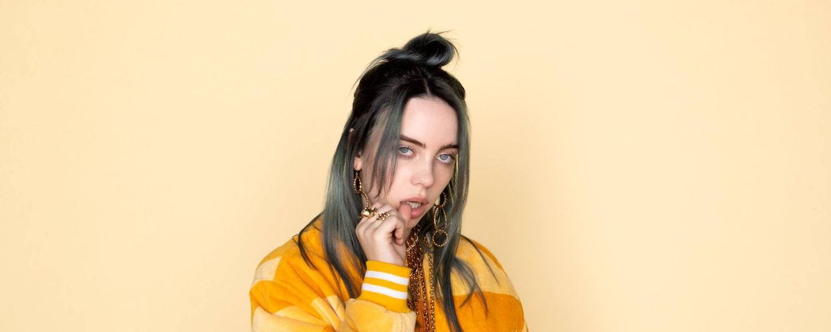 Regular photo of Billie Eilish in an orange jacket.