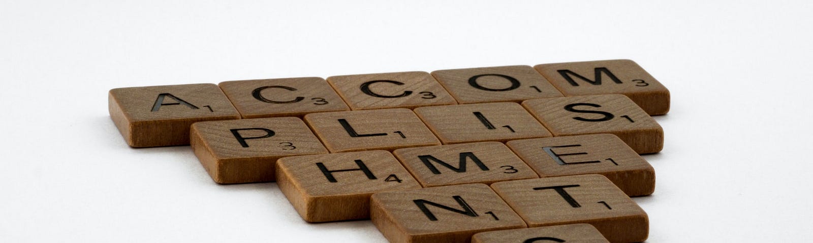 The word accomplishments written using wooden scrabble pieces.