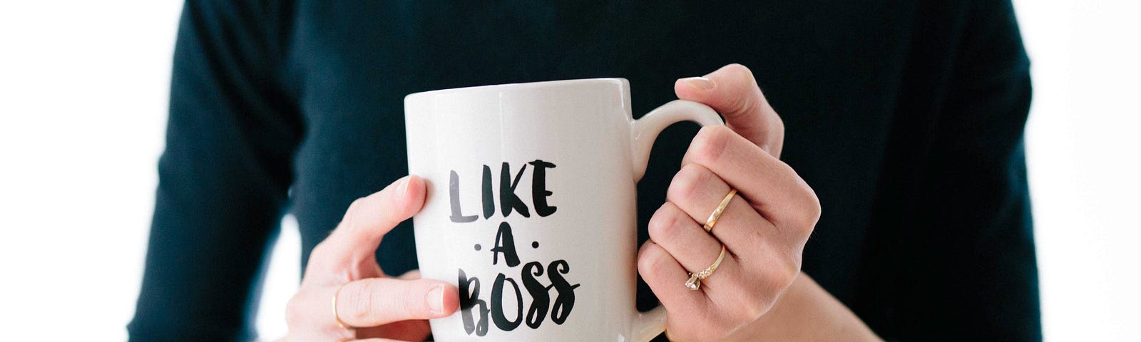 Woman’s hands holding a white mug that say, “Like A Boss”.