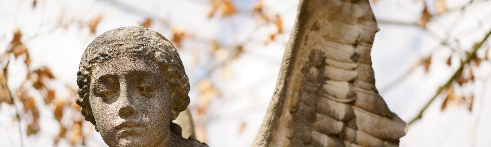 A stone sculpture of an angel, with a broken wing