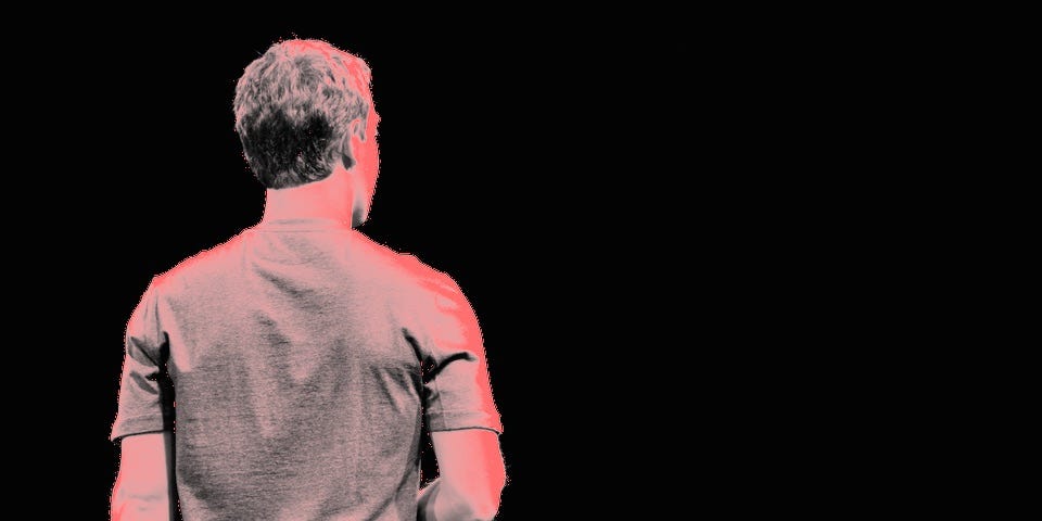 Mark Zuckerberg turns his back to an audience, tinted with a red filter.