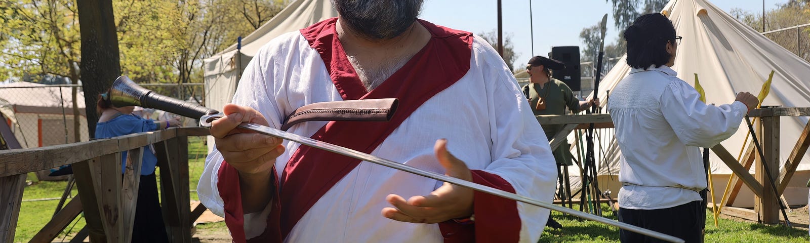 Bearded man with glasses in robe holding sword at Renaissance Fair