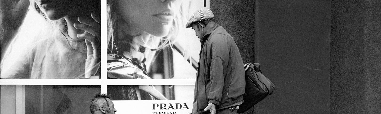 Man with grocery bags approaches a homeless man, both in front of a Prada store display