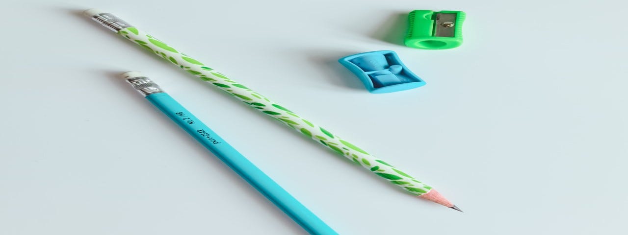 A light green pencil and sharpener and a blue green pencil and sharpener.