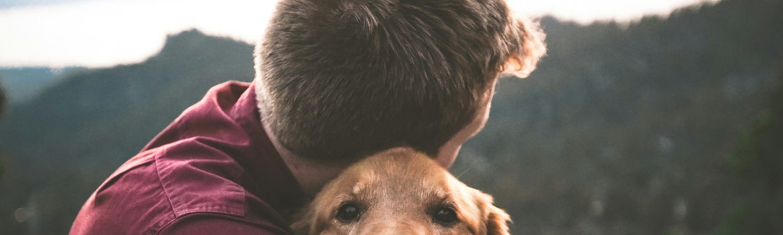 A man cuddling a happy doggo