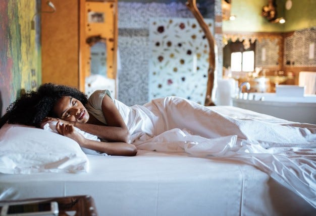 A Black woman sleeps on a bed