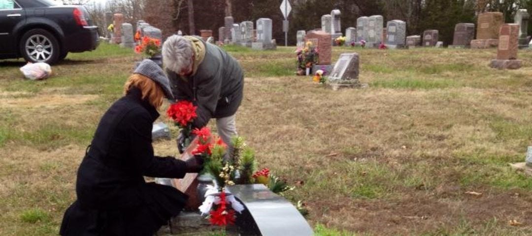 Grandmother and granddaughter decorating family headstones.