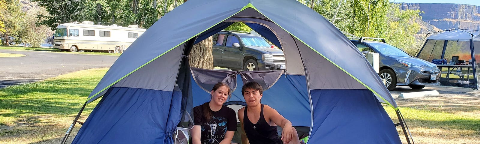 A girl with light skin and brown hair sits in a tent with a Hawaiian/Filipino boy with dark brown, almost black hair