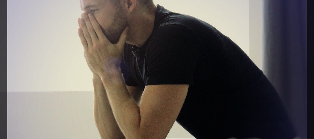 Man sitting on the edge of a bed with his face in his hands