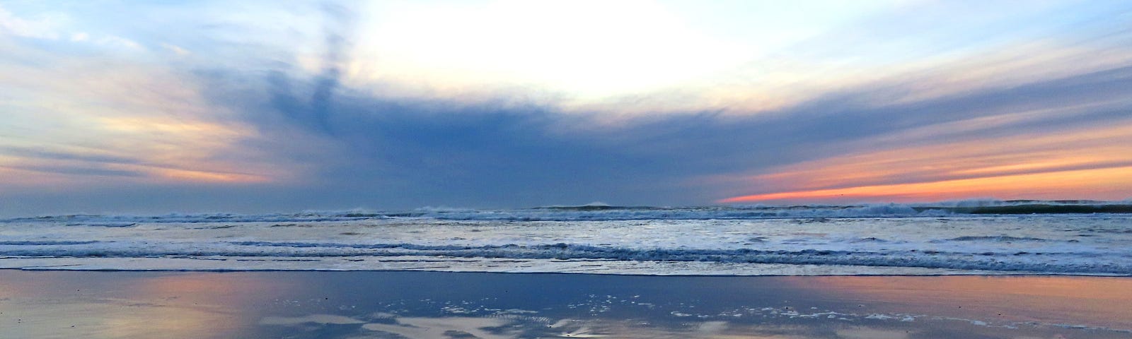 Clouds and sunset reflected on a wet beach