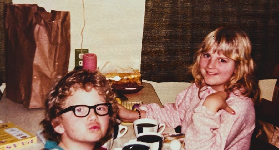 THe author at age seven with his sister, eleven, coloring easter eggs, looking into the camera.