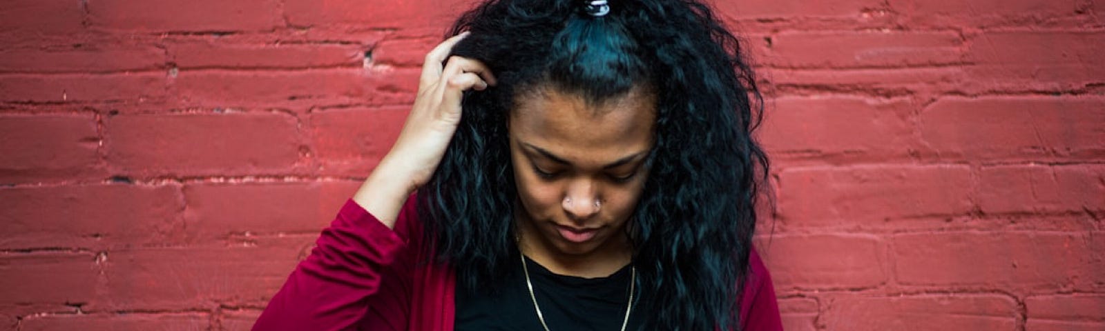 Andre Hunter took this photo of a woman looking down with her right hand in her hair.