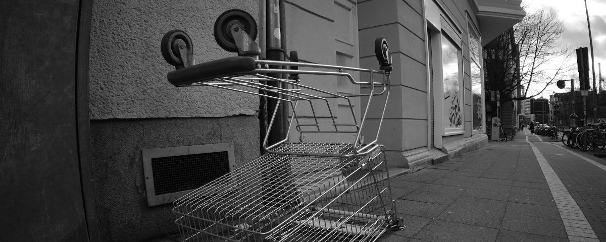 A black and white photo of an upturned shopping cart on the pavement of a Hanover street.