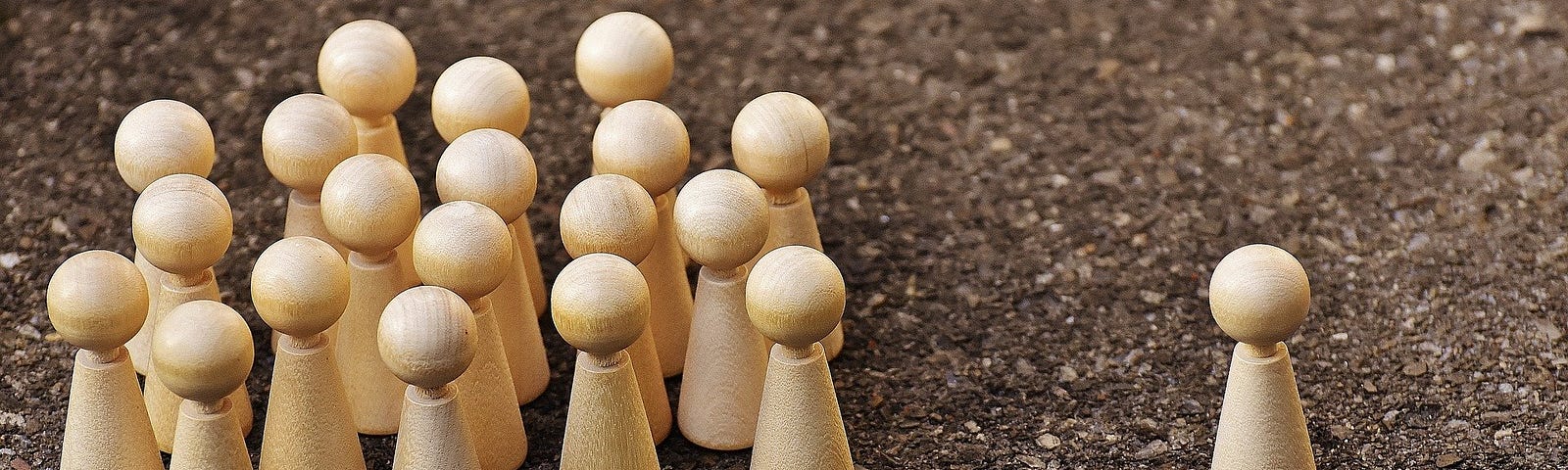 A group of wooden pegs following another wooden peg.
