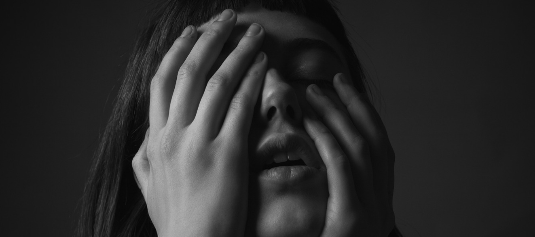 Woman mouth partly open with grief and both hands over her face