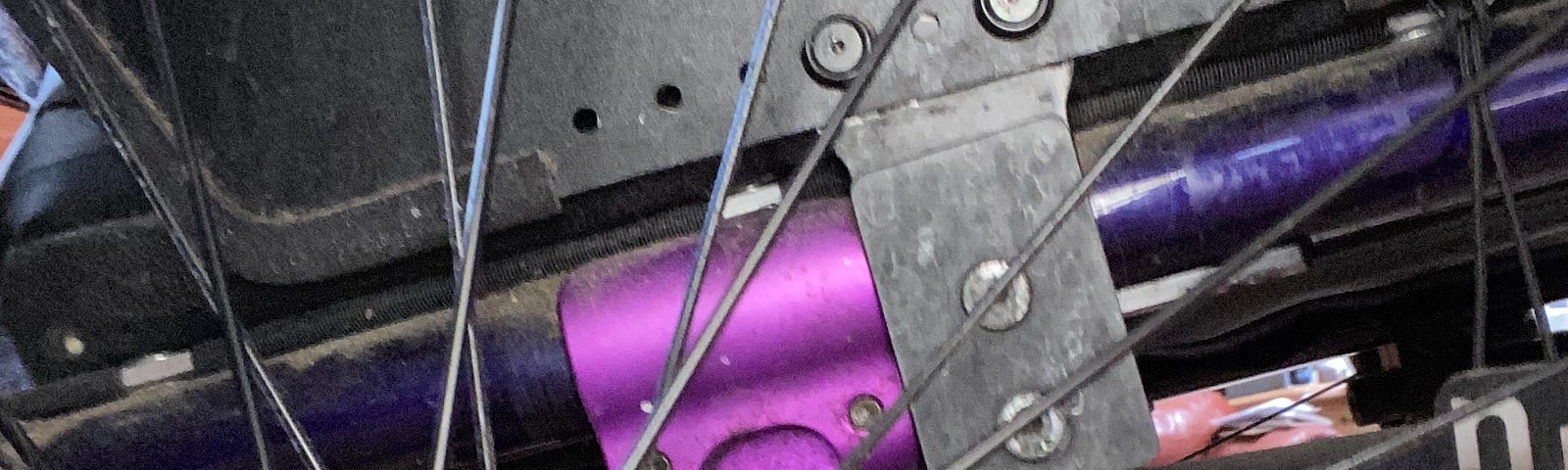 Close up detail of wheelchair spoked tire on pink and purple dirty frame.