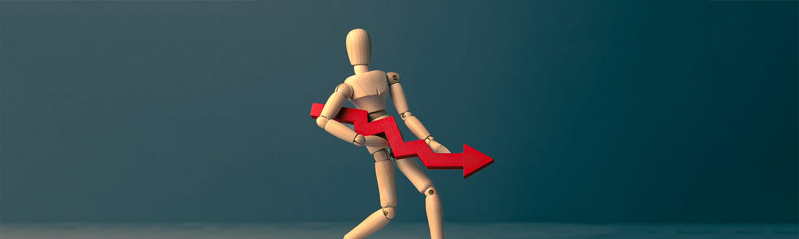 wooden figure holding downward-facing financial graph