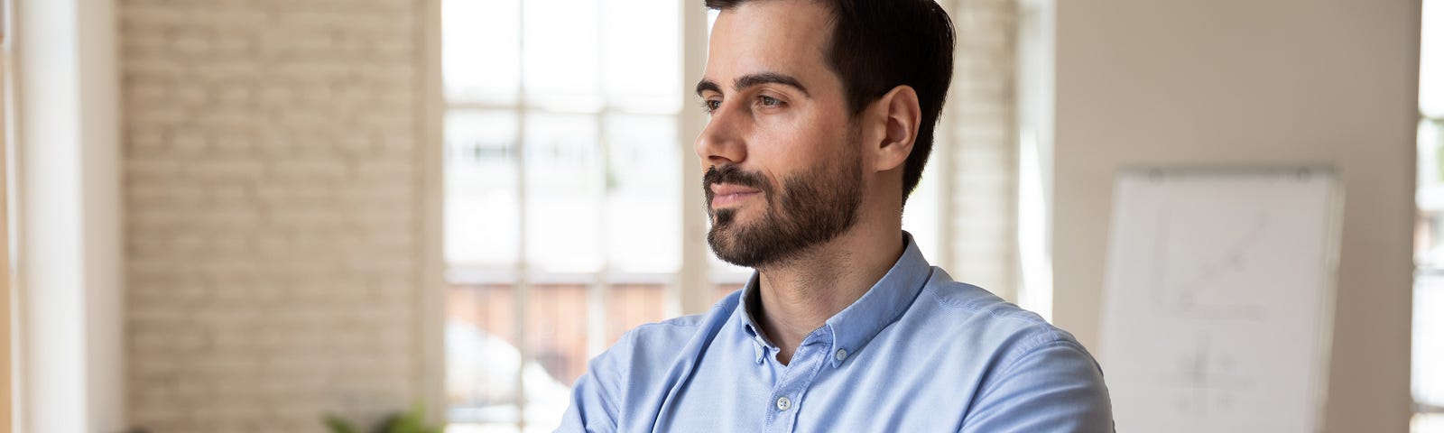 Photo of executive standing at the workplace with a thoughtful look.