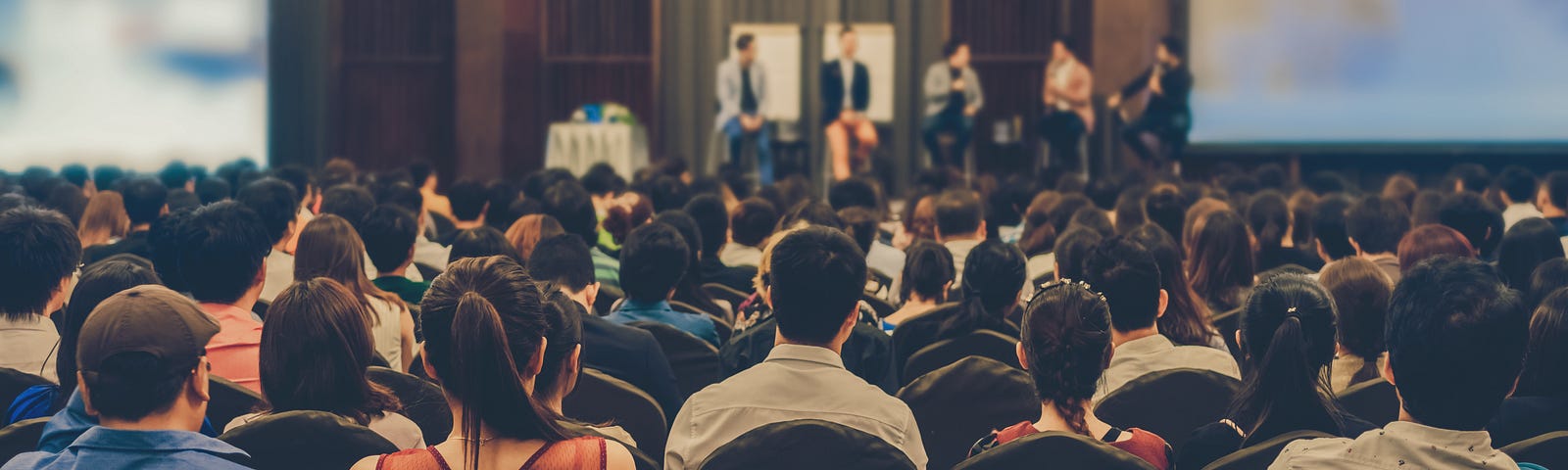 An audience listens to a speaker panel at an event.