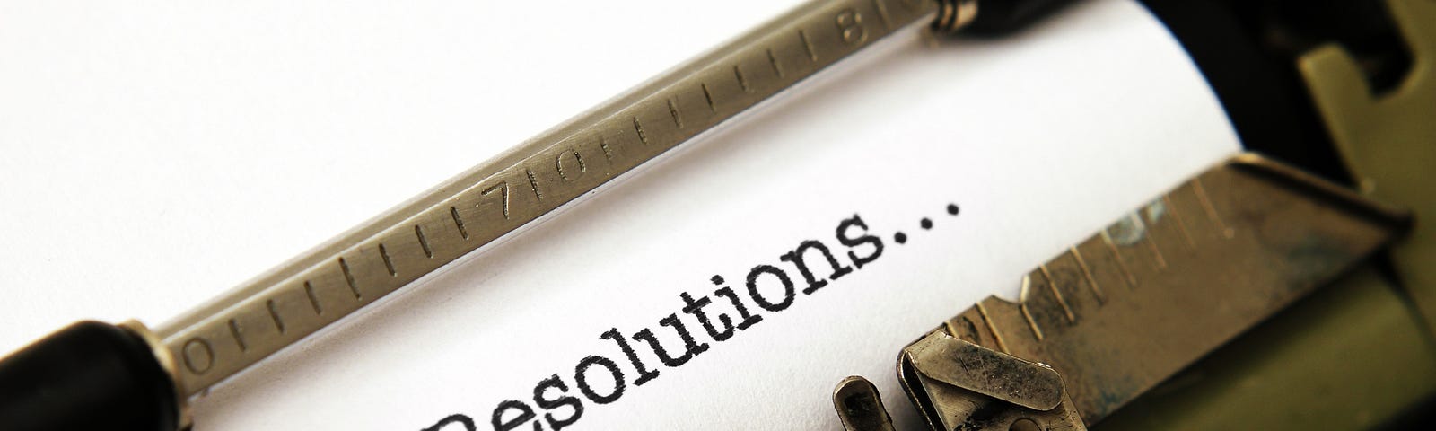 A typewriter with a piece of paper that has the text “Resolutions…” on it. (quotes, quotations, New Year’s, New Year’s resolutions)