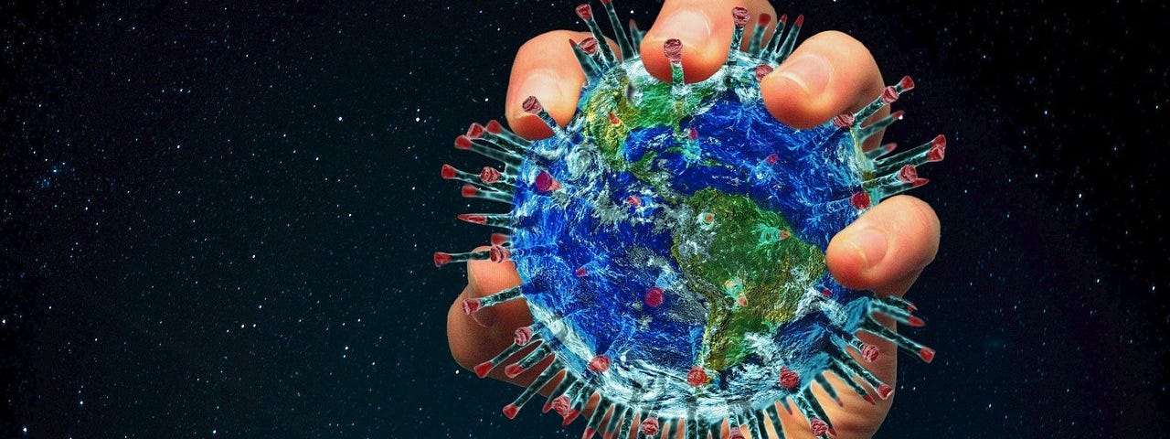 White hand (facing us) holds an illustration of a blue and green Covid-19 virus particle. The spikes protrude from the coronavirus, ending in a red color.