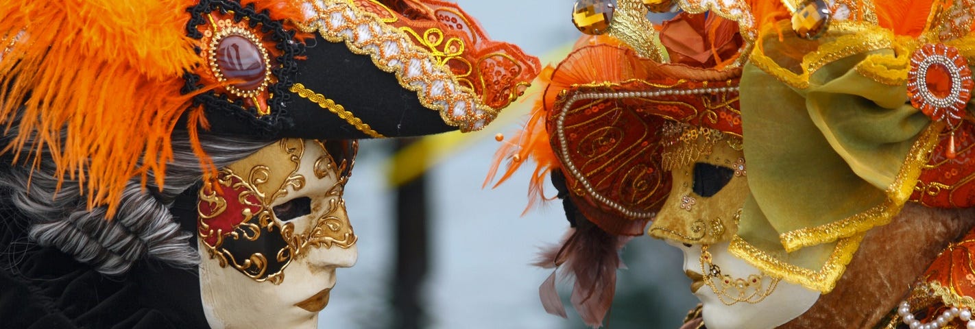 A couple facing each other wearing elaborate masks and costumes at the 2010 Carnevale in Venice in early February 2010. Their masks are elaborate and creative to match their costumes.