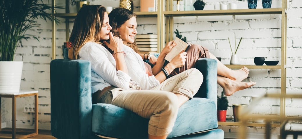 A couple reclines in a chair, leaning against one another lovingly.