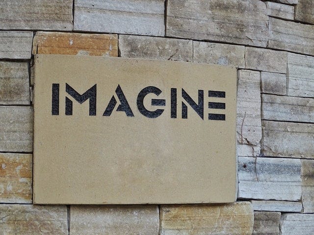 Stone wall with a wooden mdf board that reads ‘imagine’