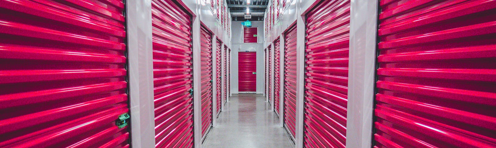 inside the hall way of storage units with pink doors