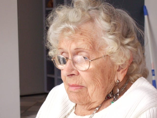 My grandmother wearing glasses and dressed in a white jumper.