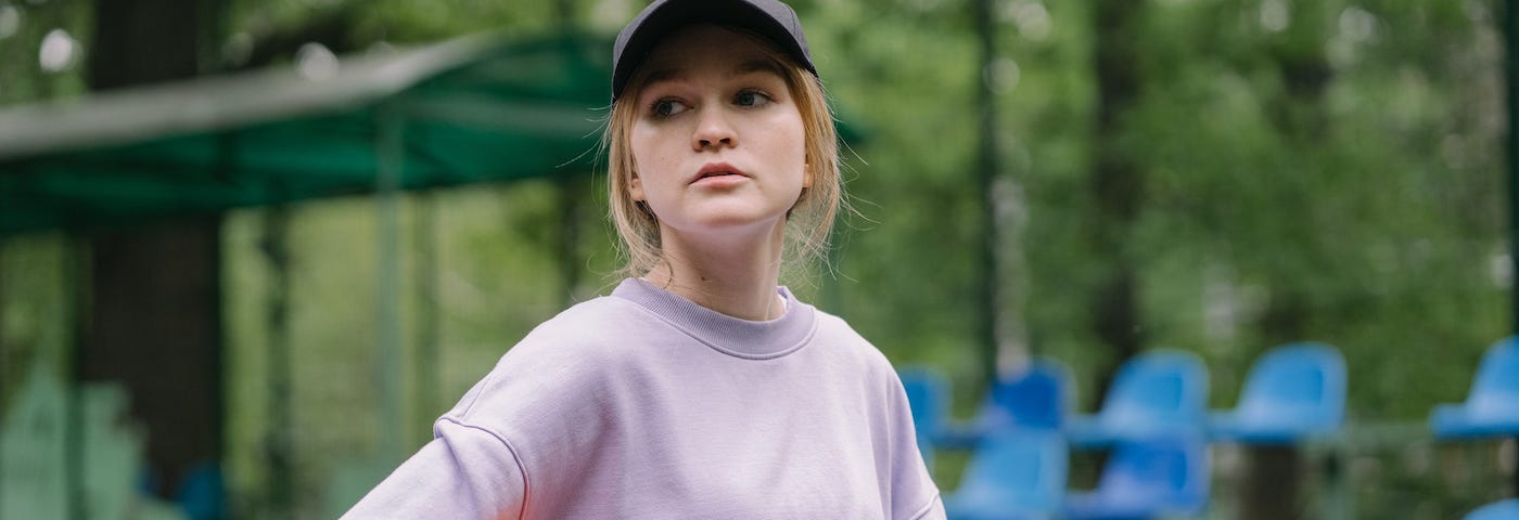 Woman facing camera, wearing a cap, and holding a basketball.