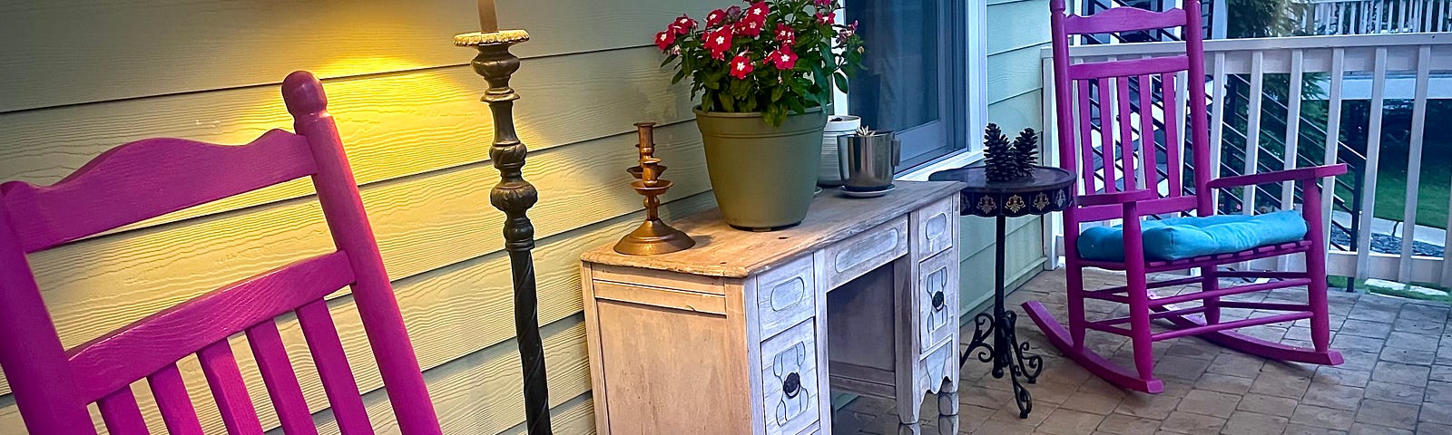 Two pink rocking chairs and some pink flowers on a front porch