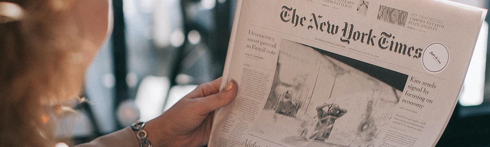 A woman reads The New York Times (Photo by Lina Kivaka from Pexels)