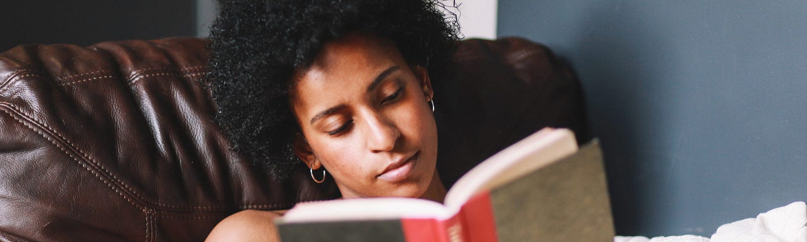 A person reading a book on their couch.