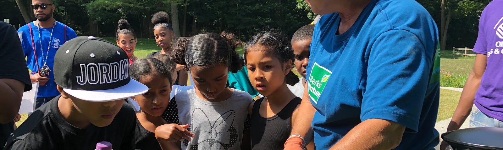 Woman gestures at a plant as children gather around