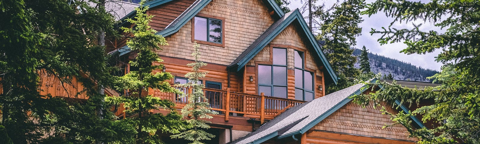 A large cabin nestled among trees. A beautiful-looking vacation home.