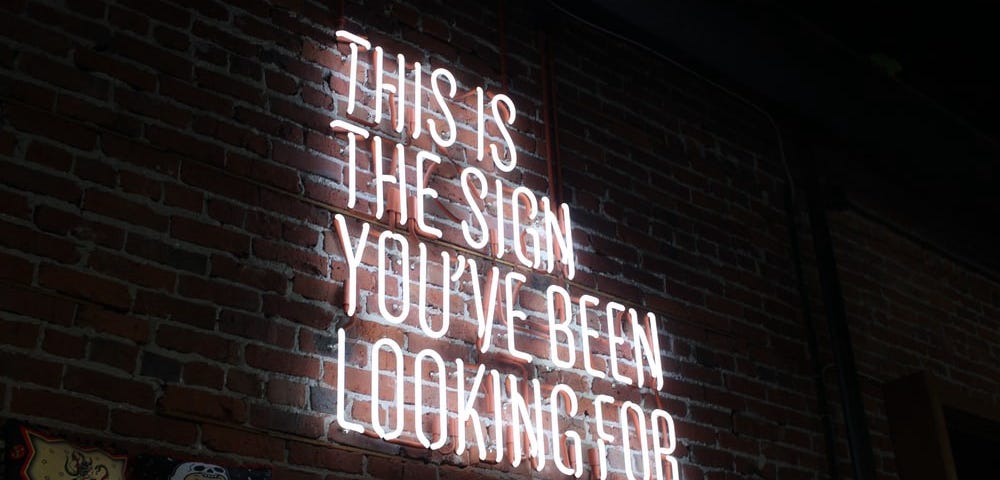 Neon sign saying: “This is the sign you’ve been looking for”.