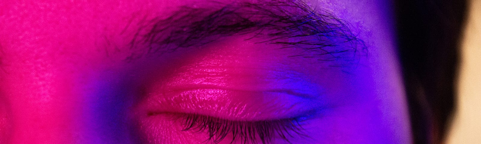 close up of persons eye closed under purple light