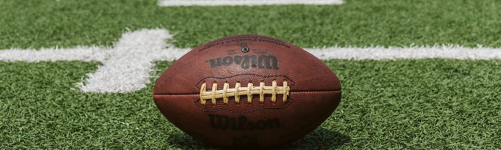 A brown football on a green field.