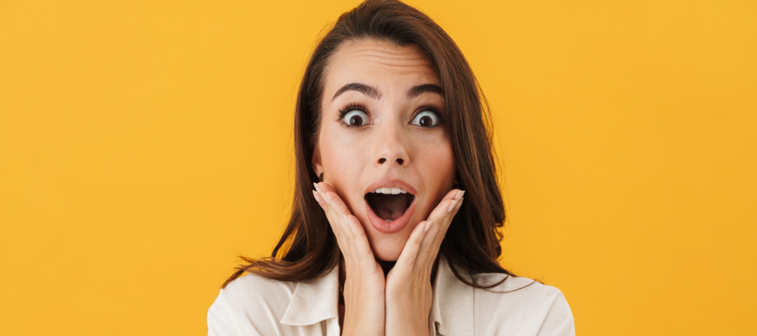 A woman looking surprised against an orange backdrop