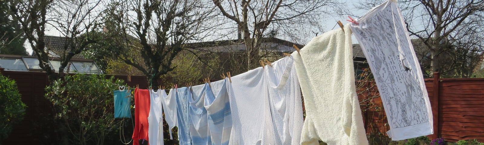 Line of washing against green grass and bare trees.