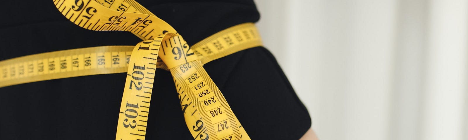 A measuring tape tied around a waist because of a fat flaw